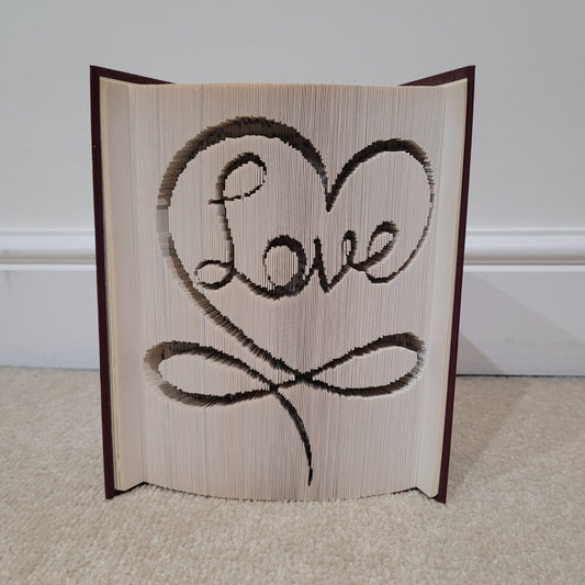 A book fold with the word "Love" on the front, with a swirl