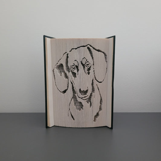 A folded book with a picture of a sausage dog/dachshund on the front.