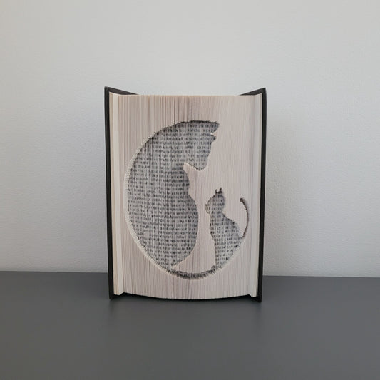 A book fold of two cats on the front, in a circle shape.
