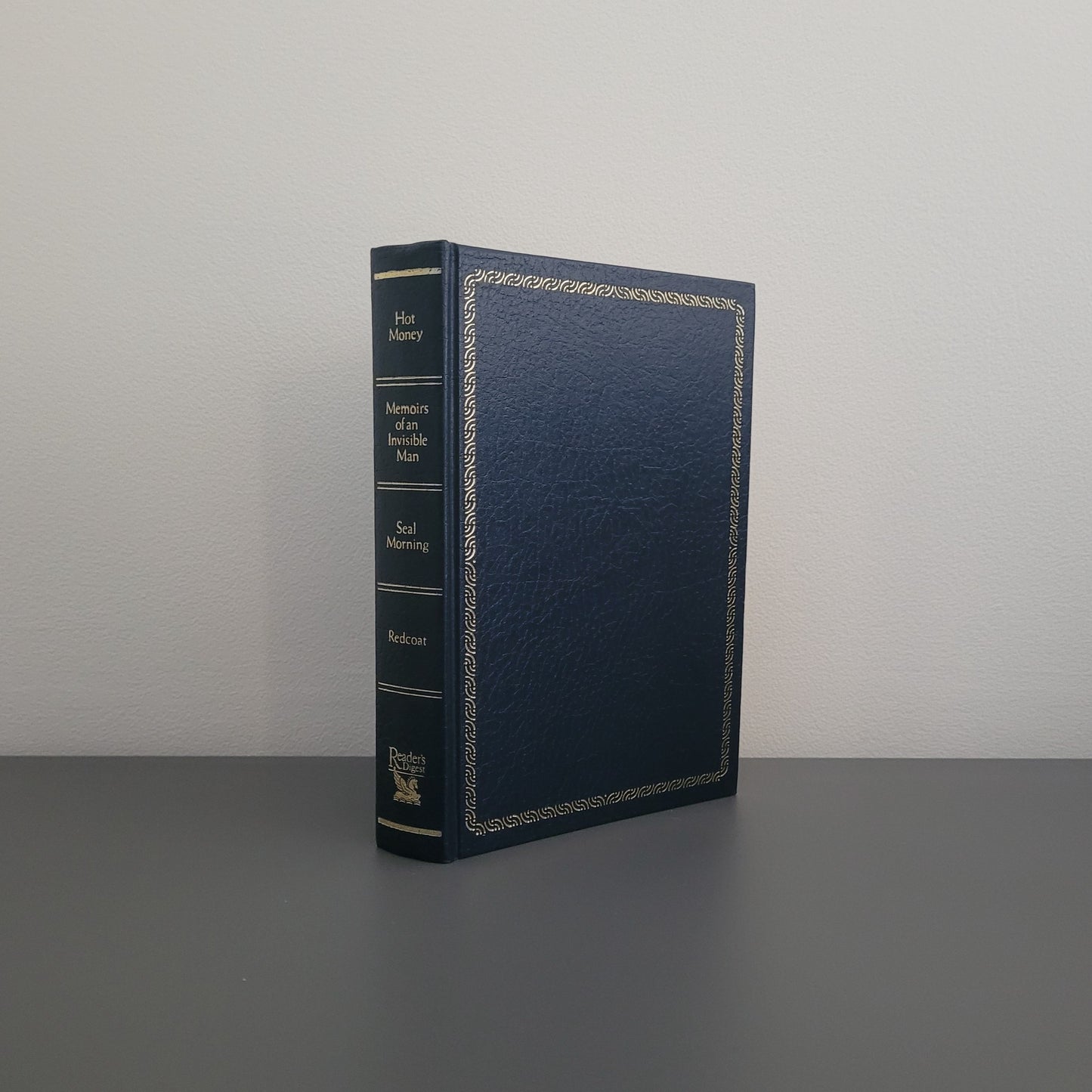 A picture of the front of the book fold - a hardback dark blue book, with a gold border.